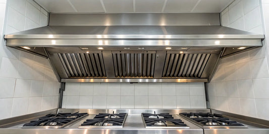 A commercial exhaust hood fan with stainless steel filters installed in a restaurant kitchen.