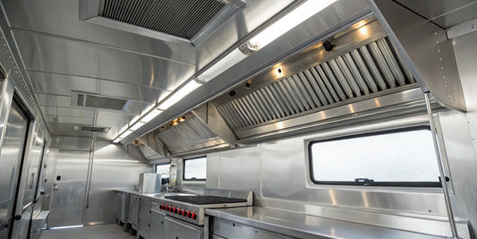 Stainless steel food truck vent hood system with an exhaust fan and filters.